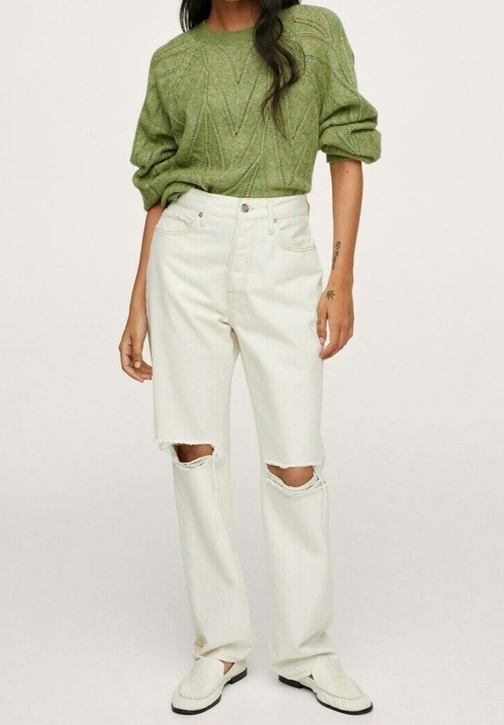 Hellgrüner gestrickter Pullover mit geometrischem Muster, kombiniert mit off-white verwaschenen Schlagjeans mit Rissen an den Knien. Weiße Slipper.