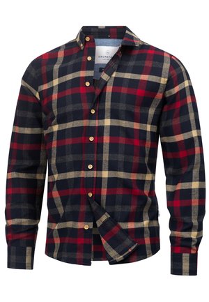 Chemise en flanelle à carreaux rouges, bleu marine et beige, avec un col boutonné, des manches longues et des boutons en bois. Présente un ourlet arrondi.