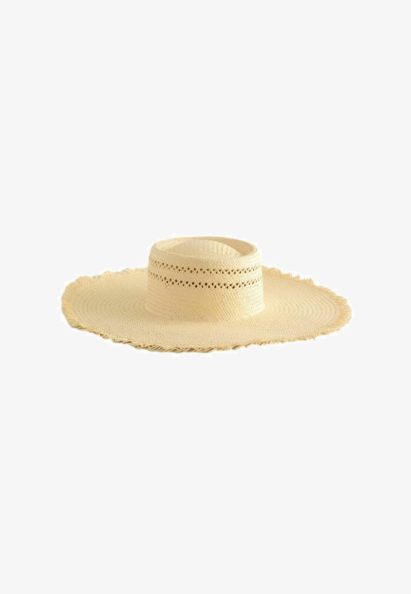 Sombrero de paja beige de ala ancha con diseño tejido y perforaciones decorativas alrededor de la copa, exhibido sobre un fondo blanco.