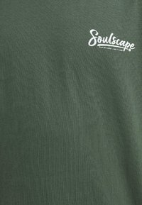 T-shirt en coton vert avec le logo blanc "Soulscape", texture lisse, col rond, et coupe décontractée. Idéal pour une tenue décontractée.