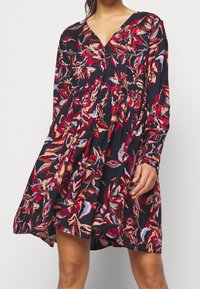 Langärmliges Blumenkleid in Marineblau, mit roten, pinken und beigen botanischen Mustern, V-Ausschnitt und gerafftem Bund. Weicher Stoff.