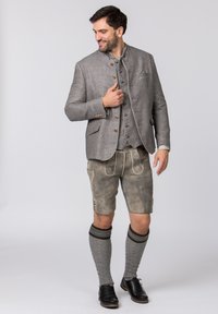 Traditional Bavarian outfit featuring a grey jacket with decorative buttons, matching vest, light-coloured lederhosen, and knee-length socks.