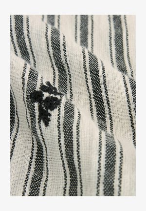 Tissu en coton présentant des rayures blanches et noires alternées avec un tissage texturé, incluant des détails de broderie florale noire.