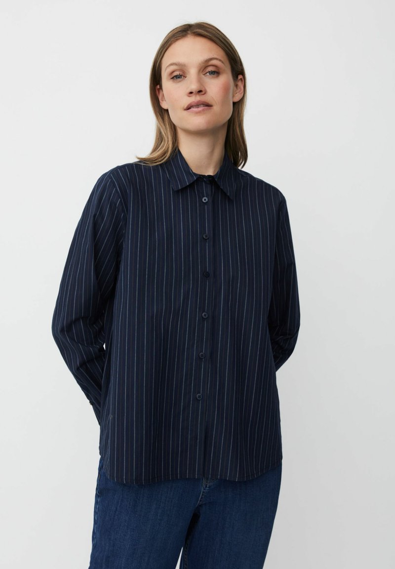 Camisa de manga larga de color azul marino con rayas verticales, frente abotonado, cuello clásico y corte relajado. Tejido suave con un brillo sutil.