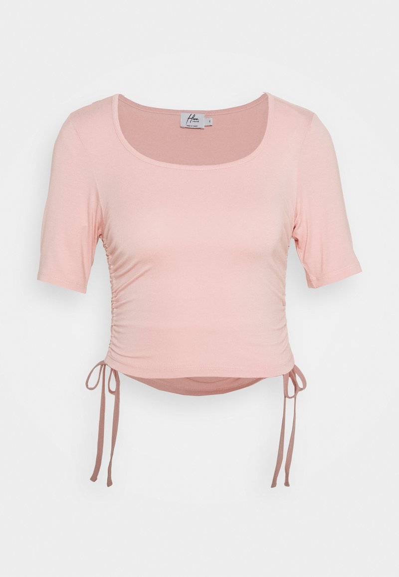 Pink short-sleeve top with a scoop neckline, gathered detailing on the sides, and adjustable ties at the hem for a customizable fit.