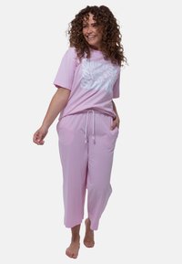 Rosa lounge set bestående av en löst sittande T-shirt med fet vit text och avslappnade, ankellånga byxor med dragsko i midjan och fickor.