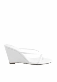 Sandale à talon compensé blanc avec une fine boucle au niveau des orteils et des brides, design ouvert à l'avant et semelle plate basse.