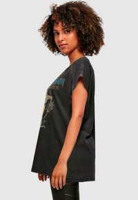 Sort oversized t-shirt med korte ærmer, prydet med grafisk tekst i blå og gul. Blødt bomuldsstof med en afslappet pasform.