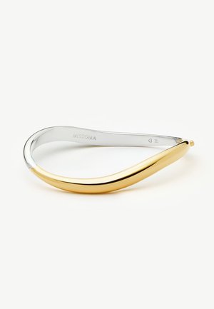 Tweekleurige metalen armband met een glad, gebogen ontwerp; goud aan de ene kant dat overloopt in zilver aan de andere kant, met "MISSOMA" aan de binnenkant gegraveerd.