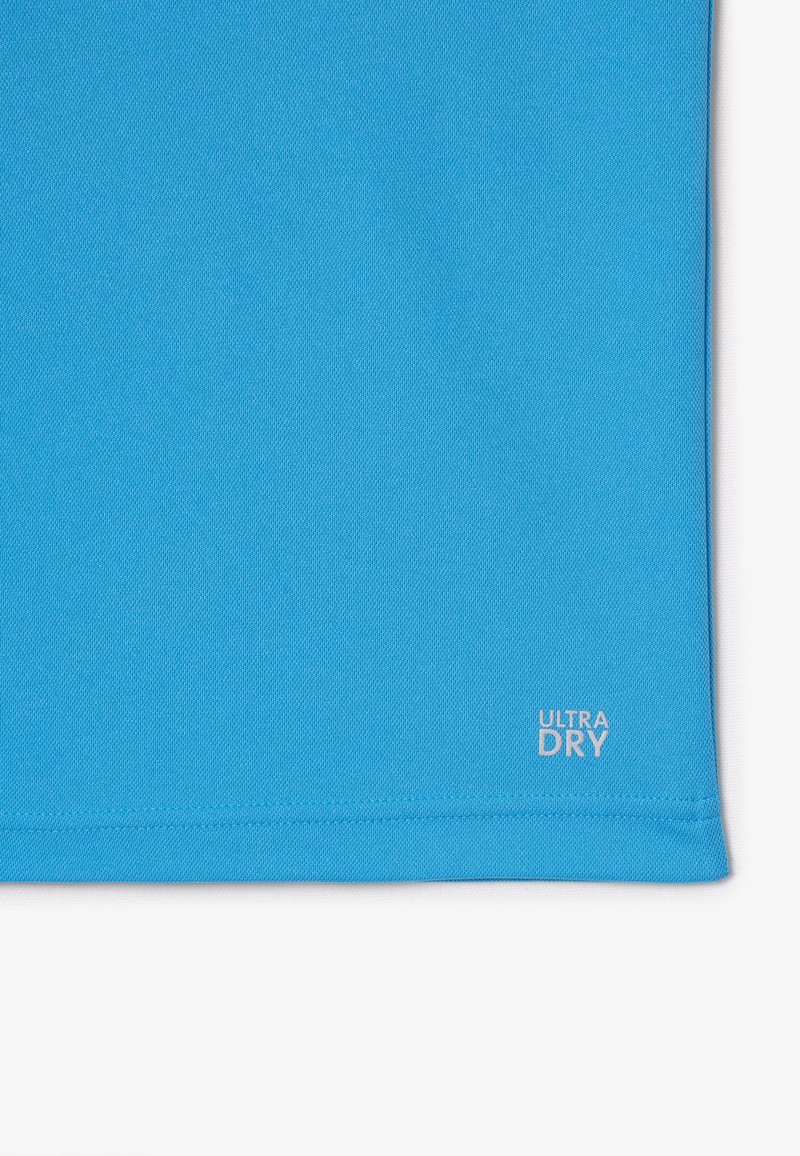 T-shirt de sport turquoise en tissu évacuant l'humidité, avec une texture lisse et un petit logo "ULTRA DRY" près de l'ourlet.