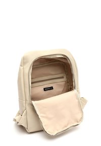 Mochila de cuero beige con cierre de cremallera, que cuenta con un interior de tela suave, un bolsillo adicional con cremallera y una textura exterior lisa.