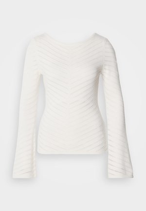 Valkoinen pitkähihaisen yläosa, jossa istuva leikkaus, korostettu kuvioiduilla siksak-kuvioilla ja venekaula-aukolla. Valmistettu pehmeästä, kevyestä kankaasta.