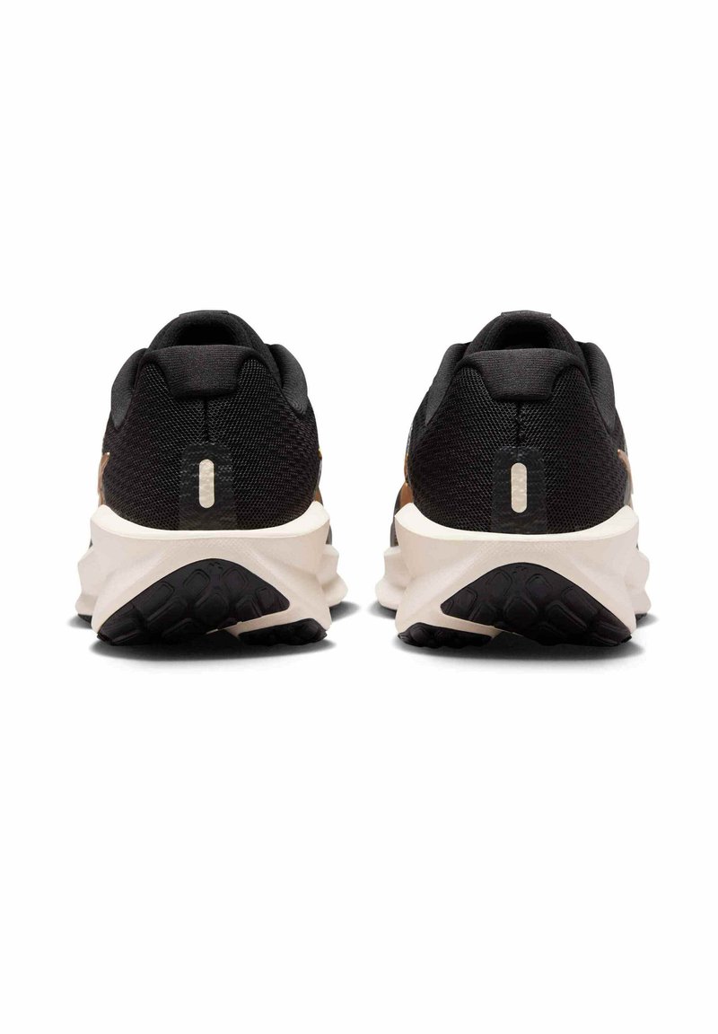 Zwarte en bruine sportschoenen met een gestructureerd bovenwerk, een gedempte zool en een kenmerkend golfpatroon op de buitenzool.