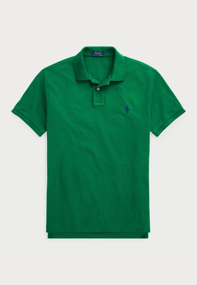 Zeleni polo majica iz bombaža, z značilnim ovratnikom, gumbnim zapiranjem, kratkimi rokavi in modrim vezenim logotipom na prsih.
