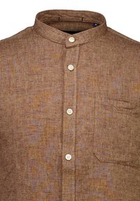 Brązowa lniana koszula z kołnierzykiem mandaryńskim, pięcioma białymi guzikami i kieszenią na piersi. Tkanina ma subtelną fakturę i wzór.