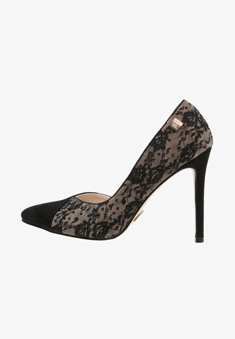 Escarpin noir à talon haut avec bout pointu, recouvert d'une dentelle transparente ornée de motifs floraux, et un petit emblème carré doré près du talon.