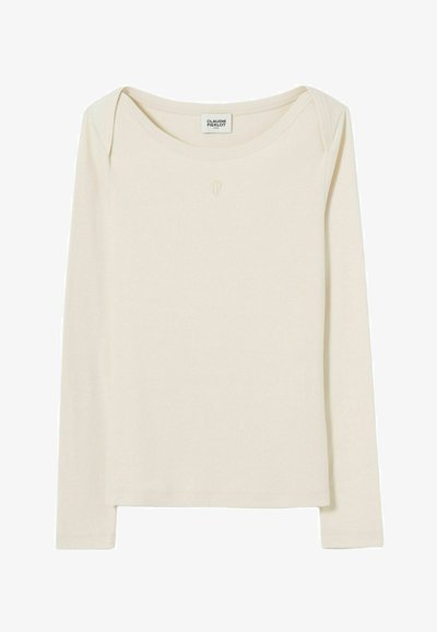 Camicia aderente a maniche lunghe di colore crema con scollatura a barca e discreto logo "CP" centrato sotto il colletto.