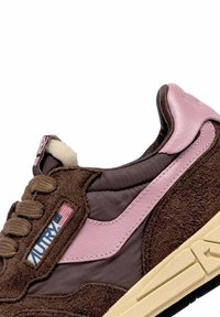 Scarpa da ginnastica marrone e rosa con dettagli in suede e pelle, suola color crema e una piccola etichetta con la bandiera americana vicino ai lacci.