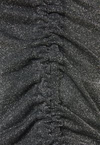 Tissu noir texturé avec des fils métalliques argentés. Présente des sections froncées et volantées créant un motif ondulé.