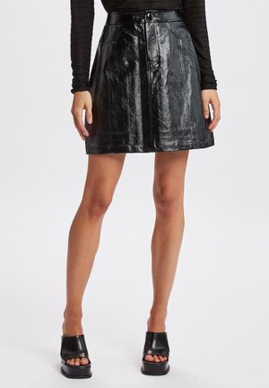 Black faux leather mini skirt with a smooth finish. Features a front button closure, two side pockets, and a flared shape.
