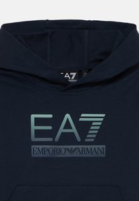 Tamnoplavi hoodie s velikim gradijentnim logotipom "EA7" i "EMPORIO ARMANI" ispisanim sprijeda. Mekana tkanina s teksturiranim završetkom.