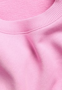 Närbild av en rosa sweatshirt med ribbat krage och mjuk tygtextur.