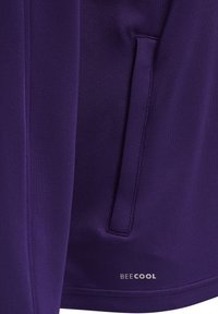 Paarse softshell jack met een ritszak, een gladde textuur en het "BEECOOL"-logo in zilver op de zoom.