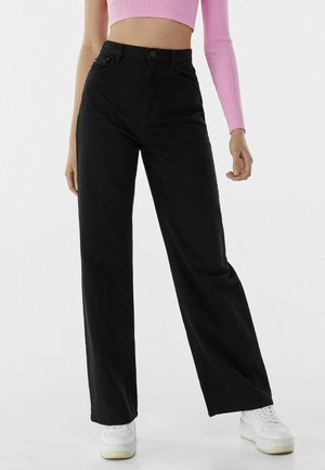 Fließende - Flared Jeans - black
