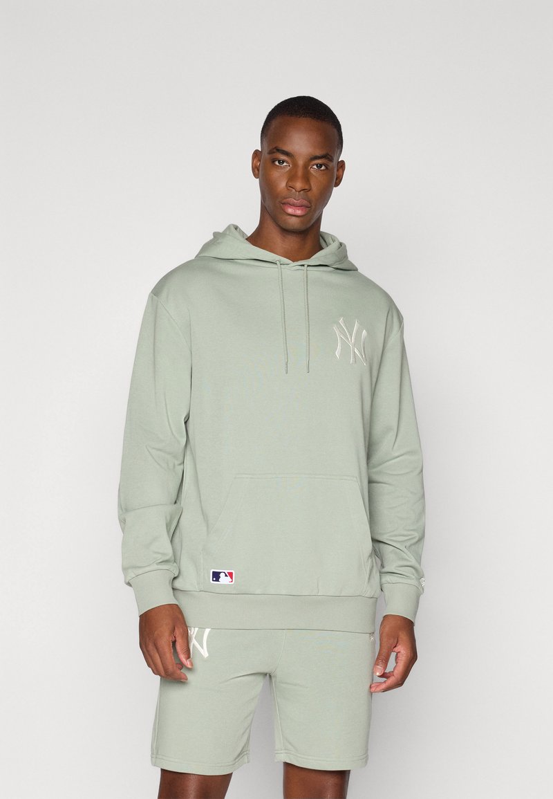 Felpa verde chiaro con tasca a marsupio, caratterizzata da un logo tono su tono sul petto e polsini a costine. Abbinata a pantaloni corti dello stesso colore.