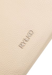 Beige strukturiertes Lederportemonnaie mit einem silbernen eingeprägten Markenlogo "RYŁKO" auf der Vorderseite. Verfügt über ein glattes, schlichtes Design.