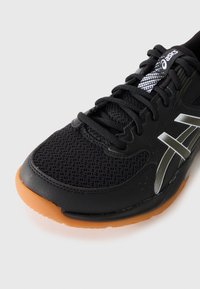 Black athletic shoe with a mesh upper, rubber outsole, and grey accents. Features black laces and a patterned tongue for added detail.