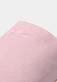 Ροζ σανδάλια Adidas με λεία, ματ υφή, με ανάγλυφο λογότυπο στο επάνω μέρος και απλό, μινιμαλιστικό σχέδιο.