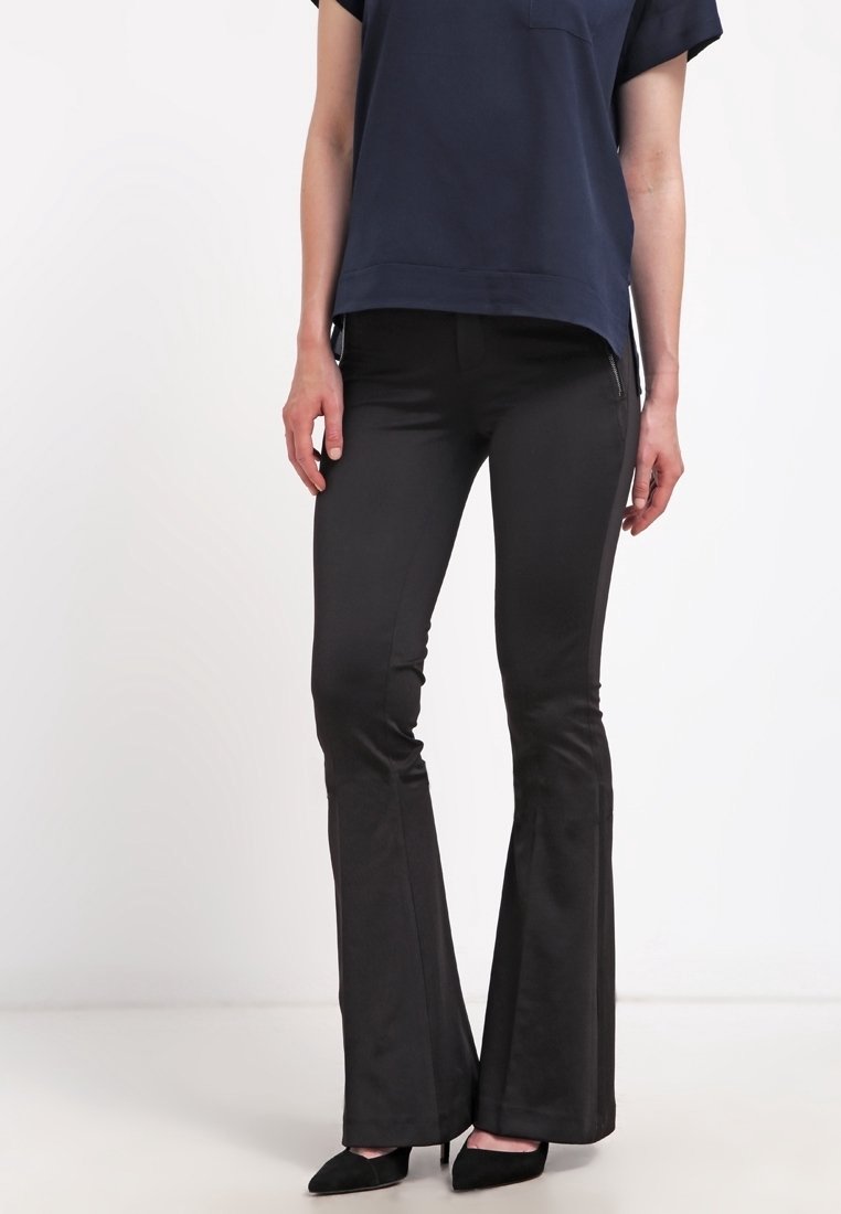 Svarta vida byxor med en jämn textur och sidoglidsektioner, ihop med en marinblå kortärmad topp med en bröstficka.