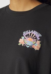 Black cotton t-shirt featuring a colorful graphic design with a circular beach scene, palm trees, and flowers. Crew neck, casual fit.