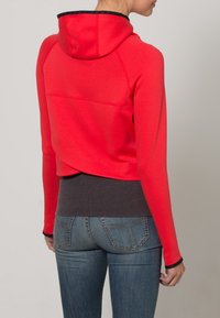 Red cropped hoodie with a hood and long sleeves, featuring a contrasting dark gray bottom band and black trim on the cuffs.