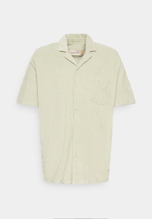 Chemise à manches courtes en vert clair, en tissu doux, avec un design à boutons sur le devant, un col pointu, une poche poitrine unique et une finition texturée.
