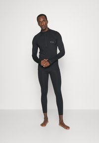 Czarna bluzka z długim rękawem i zamkiem błyskawicznym o dopasowanym kroju, z otworami na kciuki, w zestawie z dopasowanymi legginsami, wykonanymi z elastycznego materiału.