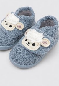 Chaussons en velours bleu avec une texture douce, ornés d'une appliqué de visage de mouton à l'avant et d'une lanière Velcro pour un enfilage facile.