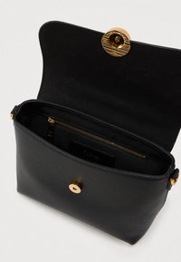 Crna kožna torbica s zlatnim okruglim kopčanjem, teksturirana vanjština, unutarnji zip džep i glatka podstava.
