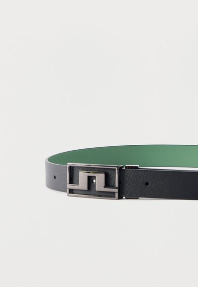 Μαύρη δερμάτινη ζώνη με πράσινη εσωτερική επένδυση και ασημένια γεωμετρική ορθογώνια αγκράφα σε λευκό φόντο.