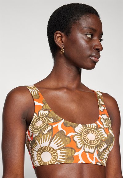 Top corto de estampado floral en naranja, crema y verde. Con tirantes anchos y tejido texturizado con un diseño ajustado.