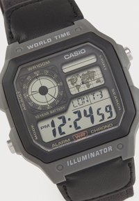 Montre numérique Casio avec un boîtier rectangulaire en plastique gris, un bracelet en cuir noir, un grand affichage LCD, une fonction d'heure mondiale et plusieurs boutons.