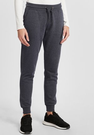 Mørkegrå joggebukser med strikk i livet, smalninger ved anklene, og en myk tekstur, sammen med svarte treningssko.