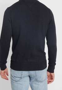 Ciemnogranatowy sweter z miękkiego materiału, o dopasowanym kroju, z prążkowanymi mankietami i schludnym wykończeniem u dołu.