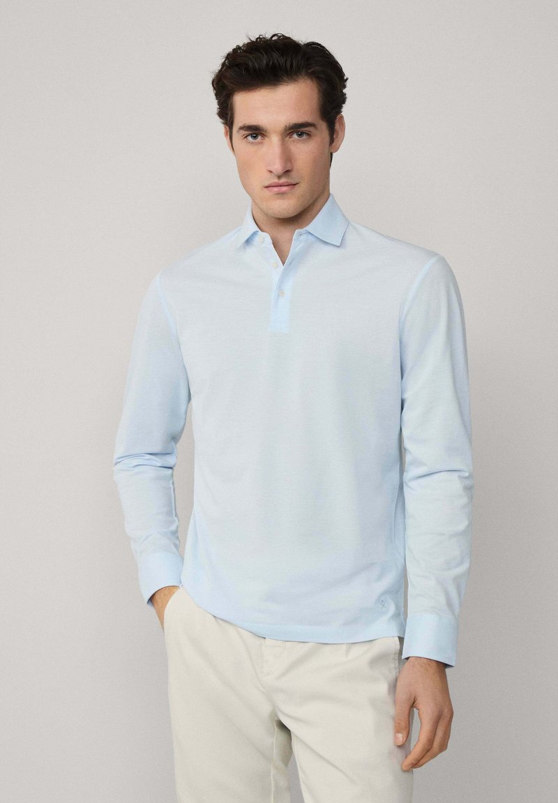Svijetloplava dugosveđa polo majica s gumbom na ovratniku, izrađena od mekanog materijala. Sadrži suptilnu teksturu i dizajn slim fit.