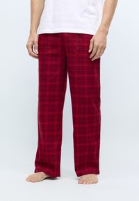 Pantalon de pyjama à carreaux rouges avec une coupe décontractée, doté d'une taille élastique et de deux poches latérales, fabriqué dans un tissu doux et texturé.