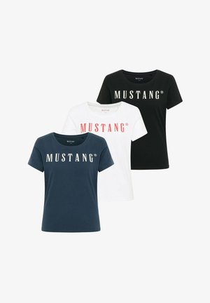 Trzy krótkie koszulki z okrągłym dekoltem w kolorach czarnym, białym i granatowym, każda z nadrukiem "MUSTANG" na piersi w kontrastowych kolorach.