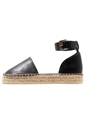 Sandale espadrille en cuir noir avec bout pointu, semelle en jute, et bride de cheville dotée d'une boucle en métal doré. Fini lisse, design minimaliste.