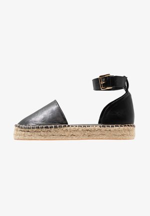 Sandalha de espadrille preta em couro, com biqueira pontiaguda, sola de corda de juta e tira no tornozelo com fivela em tom dourado. Acabamento liso, design minimalista.