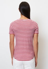 Rød og hvidstribet t-shirt med korte ærmer, rund halsudskæring og let buet kant. Stoffet ser glat og let ud.